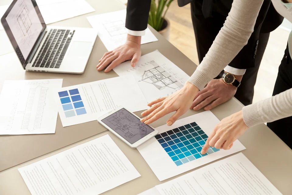 Vue rapprochée des concepteurs de l'Intérieur travail d'équipe avec pantalon et plans de construction de maison sur bureau, architectes travaillant avec une palette de couleurs bleues pour choisir la meilleure peinture pour la rénovation de la maison