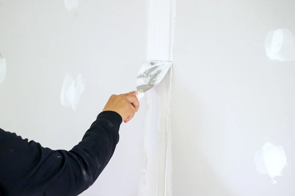 main de travailleur utilisant des joints de plafond de plâtre au chantier de construction