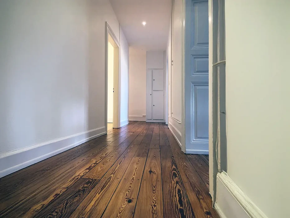 Couloir d'appartement rénové avec parquet en bois massif aux veines prononcées