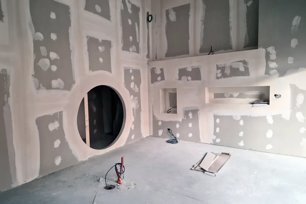 Le travailleur met des carreaux sur le mur dans la cuisine