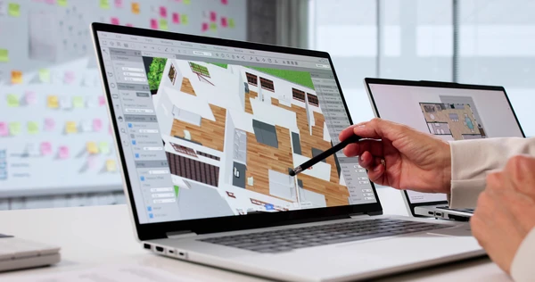 Deux personnes travaillent sur des plans d'architecture d'int&eacute;rieur autour d'une table en bois