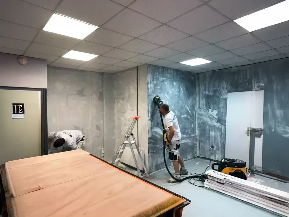 Peintre professionnel appliquant de la peinture murale bleue dans une pièce en rénovation, utilisant un escabeau aluminium