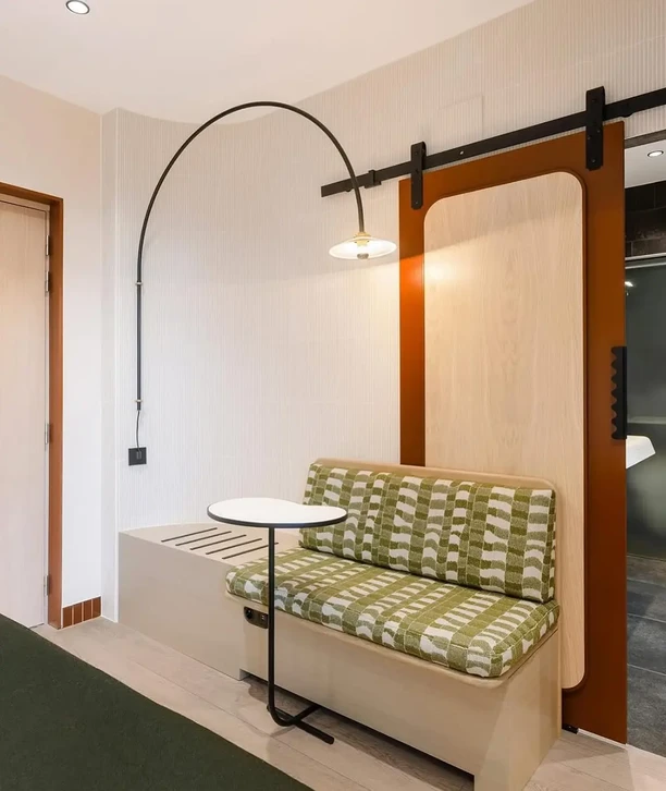 Personne tenant un pinceau plat à virole dorée et manche en bois au-dessus d'un pot de peinture blanche dans un environnement intérieur aux murs blancs